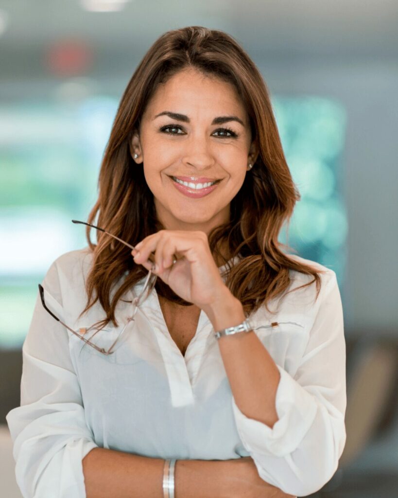 Mulher com óculos na mão e sorrindo